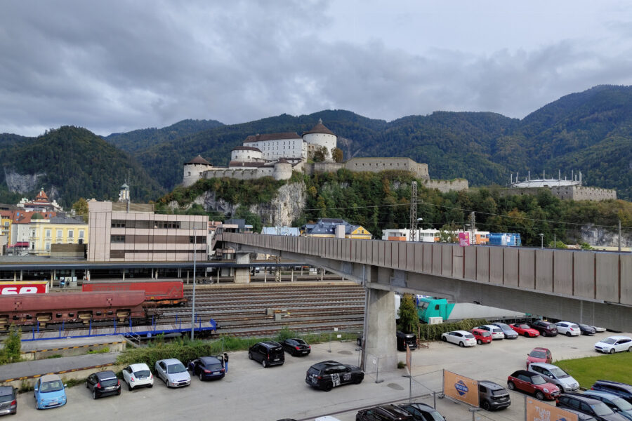 Über die Fußgängerbrücke wird der Bahnhof überquert, im Hintergrund die Festung Kufstein; Foto: Simon Widy